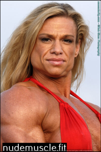 Female bodybuilder Tina Chandler shows off a red swimsuit on a beach. Image #13