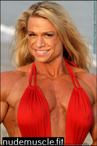 Female bodybuilder Tina Chandler shows off a red swimsuit on a beach. Image #8